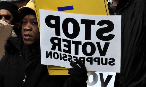 妇女在投票权游行中举着“停止压制选民”的牌子